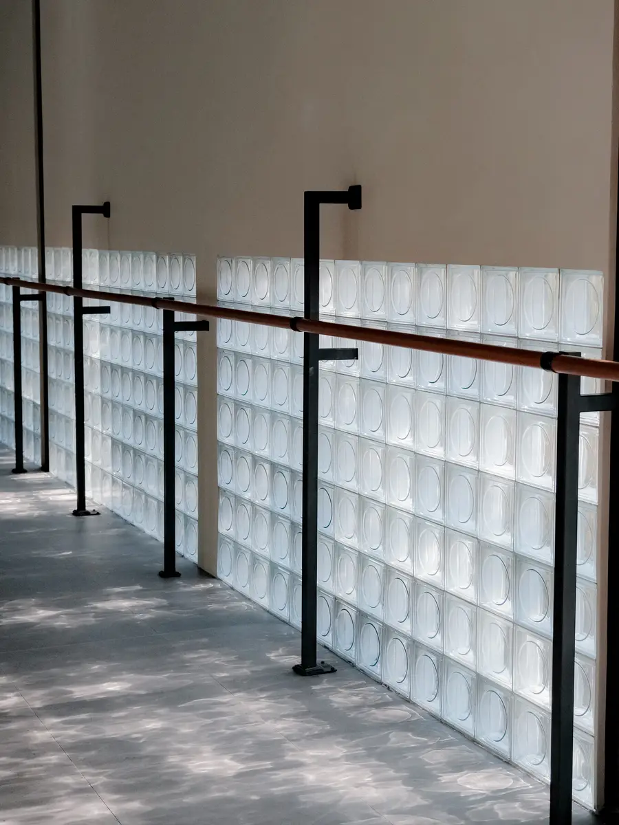 The barre rail along the glass-block wall, daylight on the studio floor