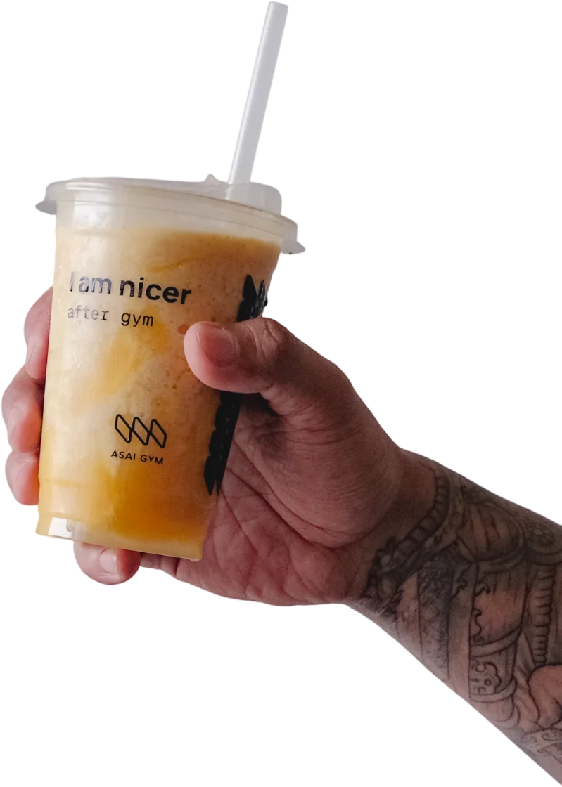 A tattooed hand raising a mango ASAI GYM smoothie